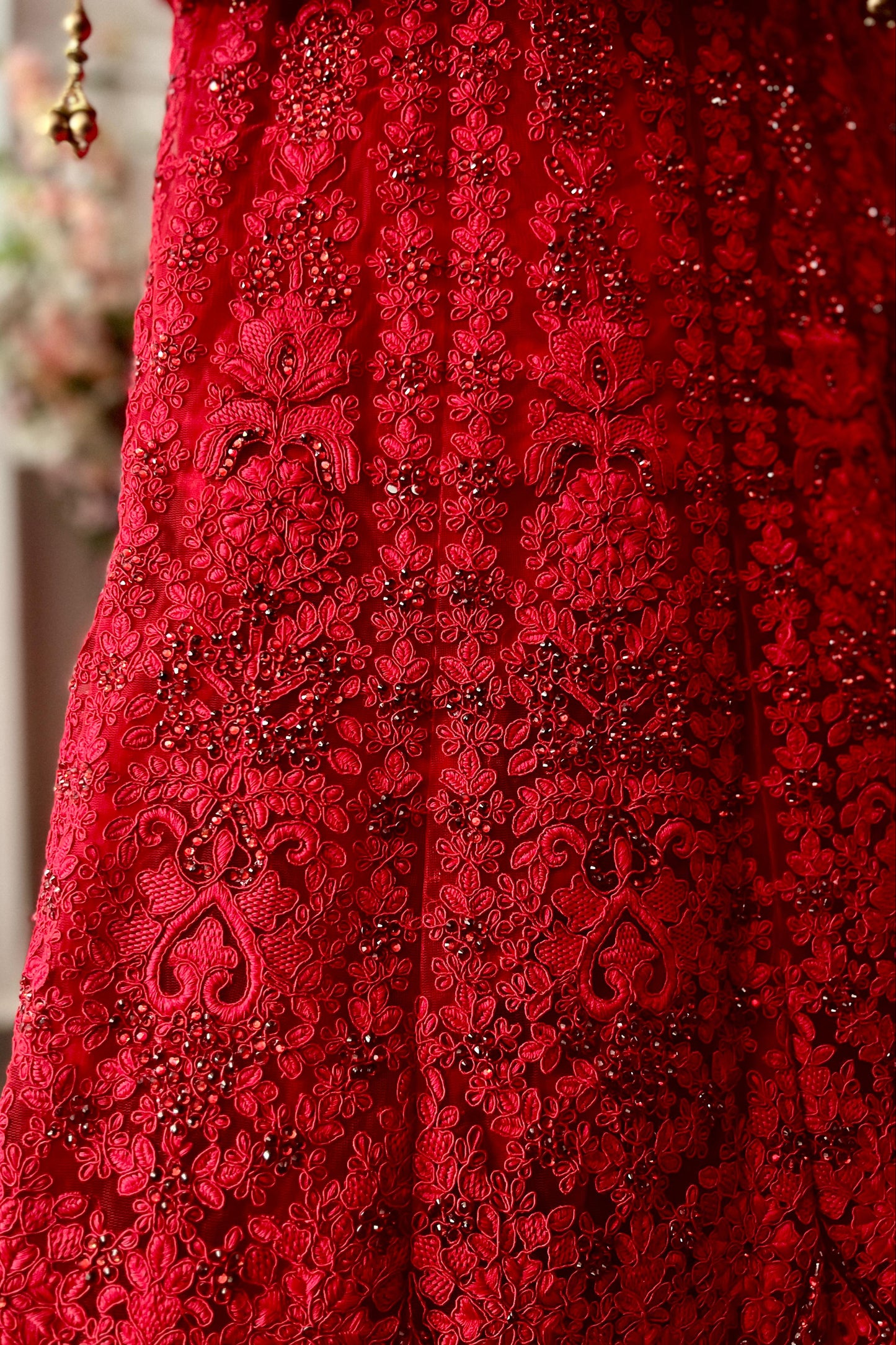Close-up of a red lace dress with intricate patterns and embellishments.