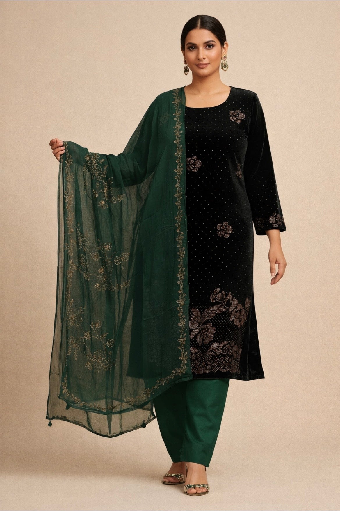 Woman wearing a black and green traditional outfit with a sheer green dupatta on a beige background