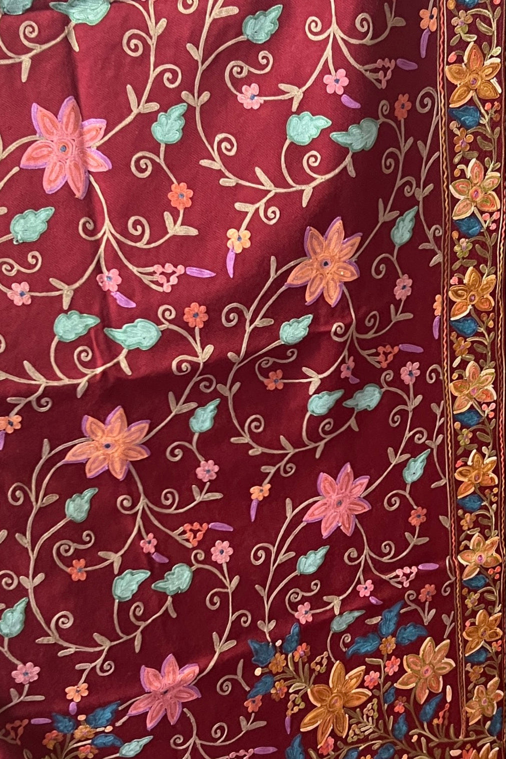 Embroidered fabric with floral patterns on a maroon background