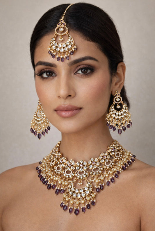 Woman wearing an elaborate gold and purple jewelry set against a neutral background